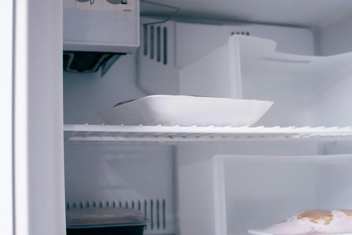 Открытое морозильное отделение холодильника с полками и продуктами.