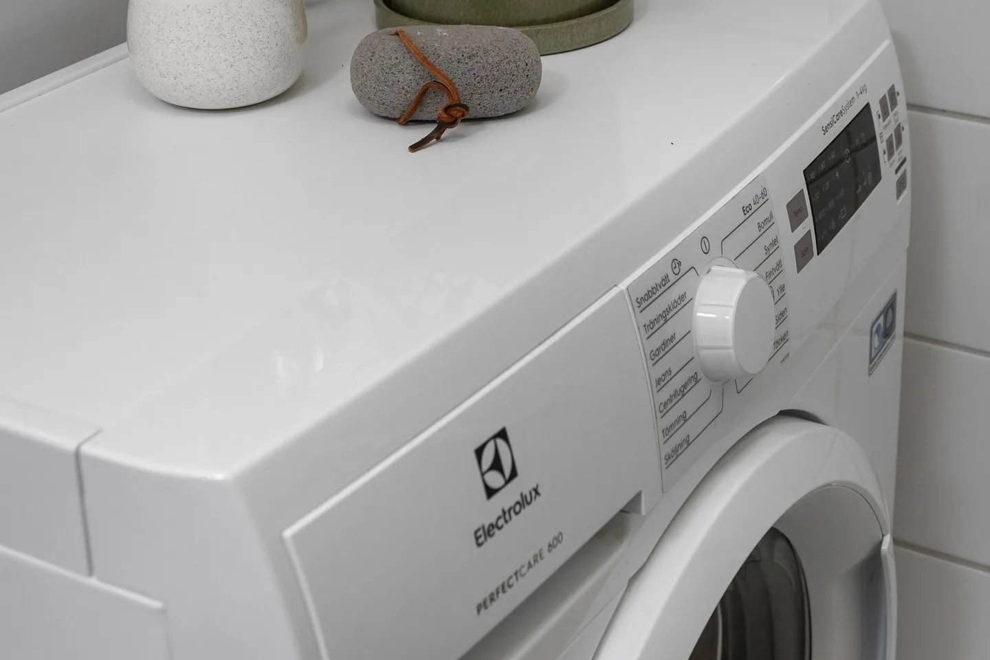Белая стиральная машина Electrolux с фронтальной загрузкой в ванной комнате.